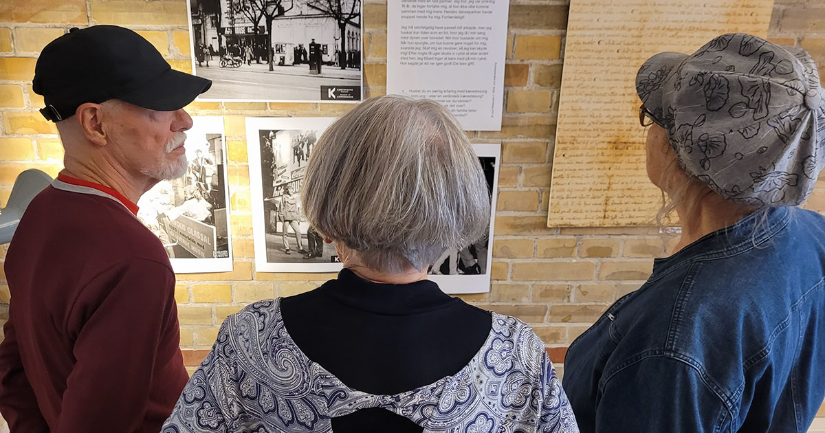 Tre deltagere i Erindringsklubben kigger på historiske fotos.