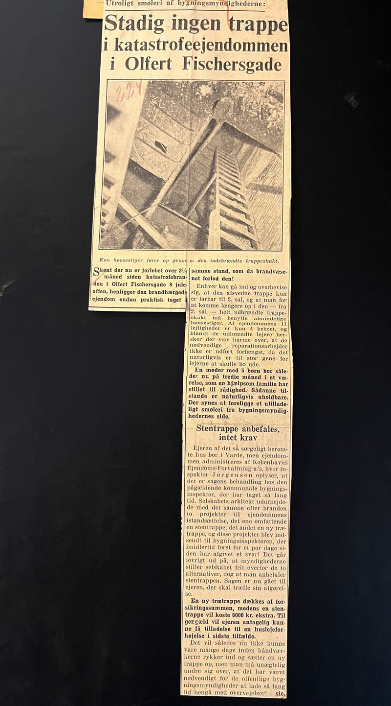Udklip fra avis med overskriften "Utroligt smøleri af bygningsmyndighederne: Stadig ingen trappe i katastrofeejendommen i Olfert Fischergade." Overskriften er efterfulgt af at foto af en træstige. Artiklen starter med "Skønt der nu er forløbet over 2 1/2 måned siden katastrofebranden i Olfert Fischersgade 8 juleaften, henligger den brandhærgede ejendom endnu praktisk taget i samme stand, som da brandvæsenet forlod den!"